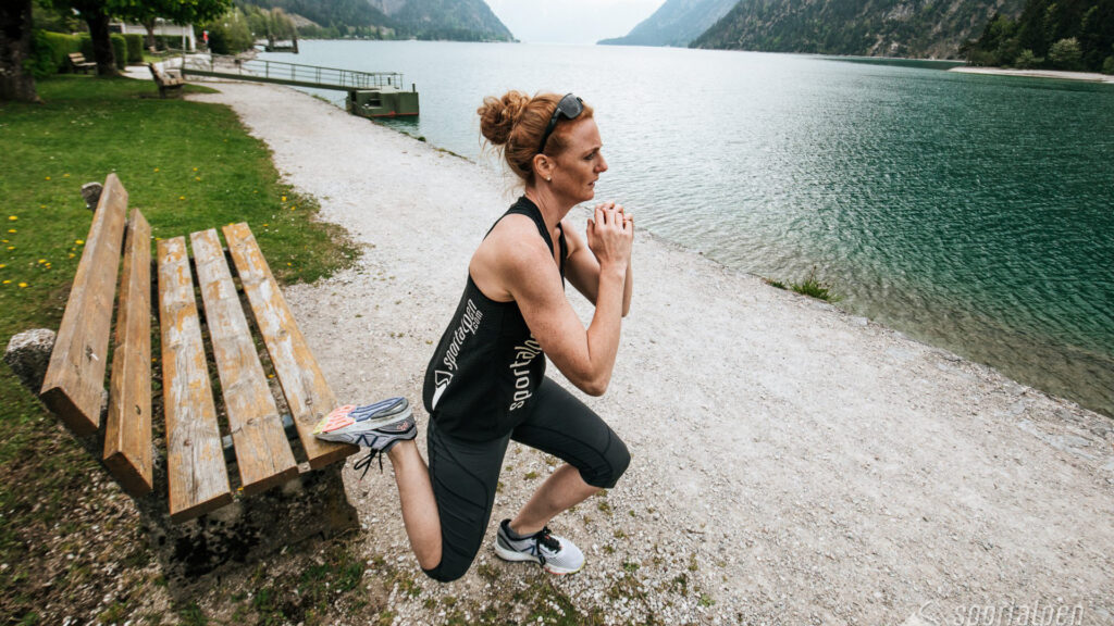 Eine Frau macht Bulgarian Split Squats am Seeufer des Achensees.