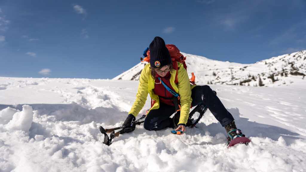 Eine Schneeschuhwanderin übt sich beim Lawinentraining im Karwendelgebirge im Umgang mit dem LVS-Gerät.