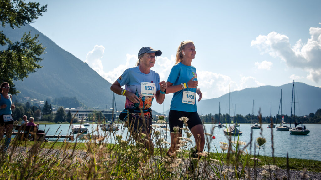 Bei sonnigem Wetter laufen zwei Frauen auf der Eventstrecke entlang des Achensees.