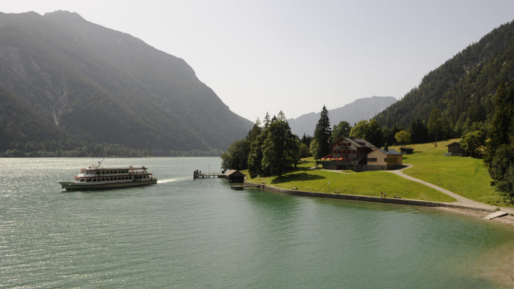Schiff auf grĂŒnem See mit Bergen im Hintergrund